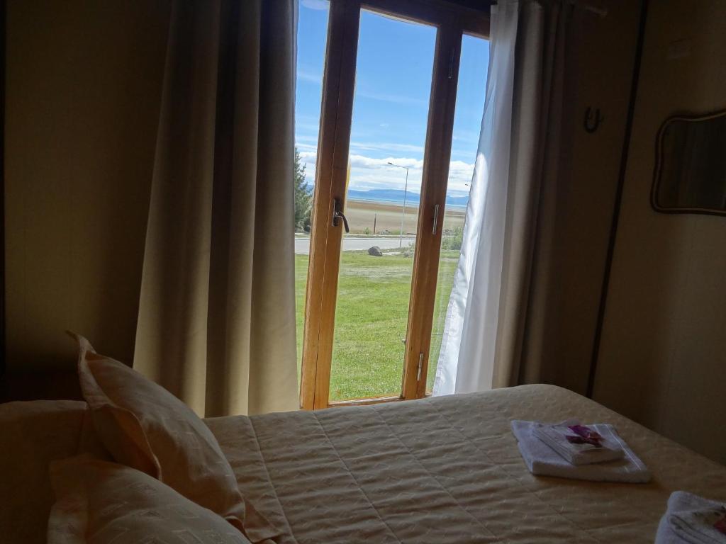 um quarto com uma cama e vista para uma janela em Cabañas Oyikil em El Calafate
