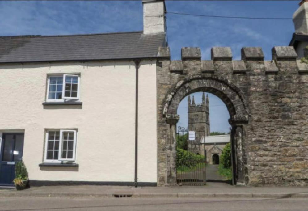an arch in a brick building with a clock tower at Church Gate Cottage - Bridestowe in Bridestowe
