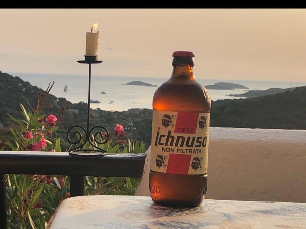 a bottle of beer sitting on a table with a candle at Appartamento Taras Sottovento - Porto Cervo in Abbiadori