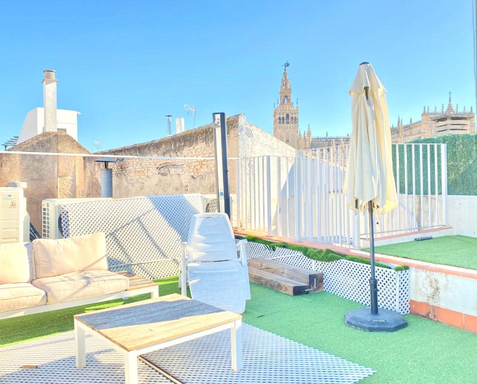 a patio with a couch and an umbrella on a roof at Top-notch downtown house with private rooftop terrace and parking opt in Seville