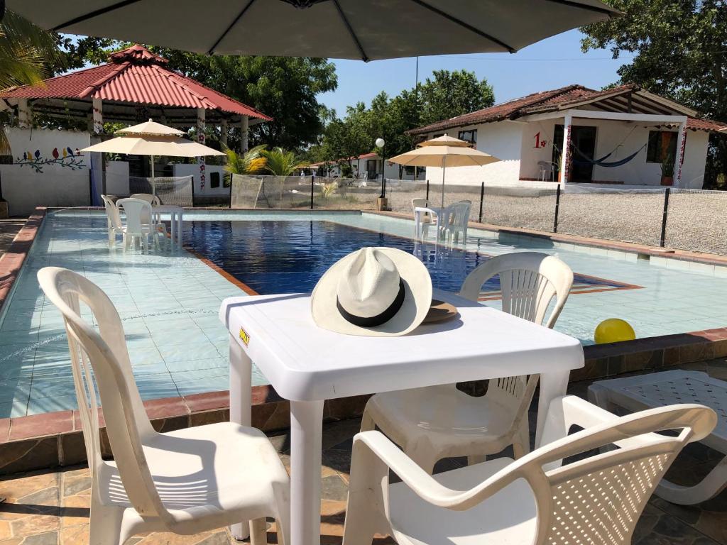 una mesa blanca con un sombrero junto a una piscina en Cabañas Campestres en Villavicencio, en Villavicencio