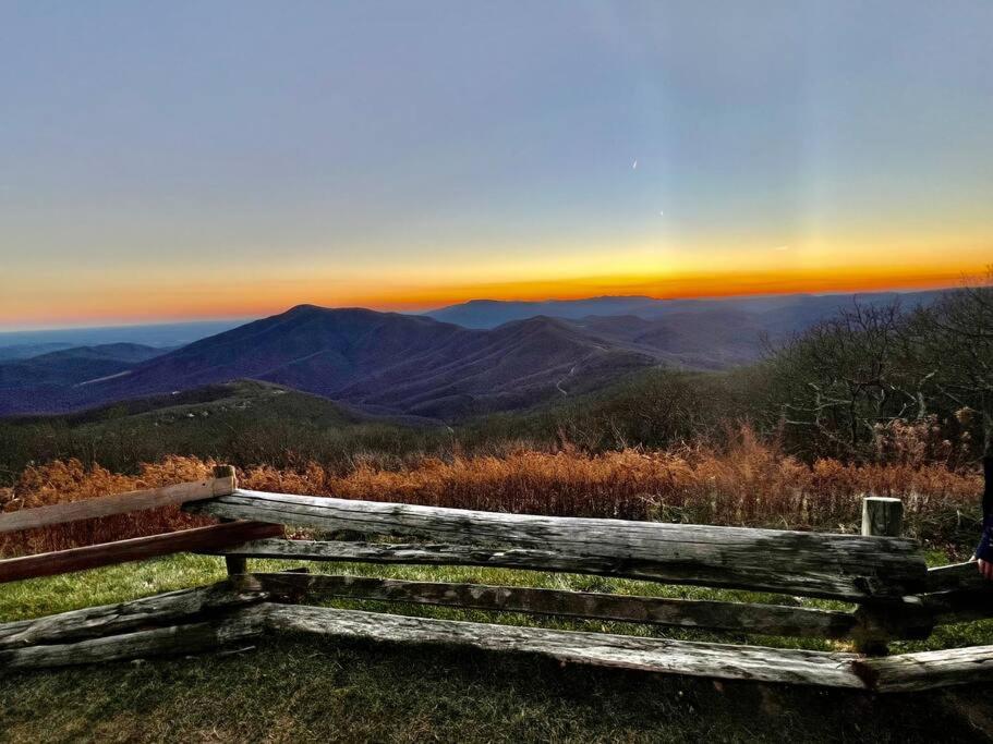 a wooden bench sitting on top of a hill with a sunset at New! Luxury Mountain Top Retreat w/Carriage House in Lyndhurst