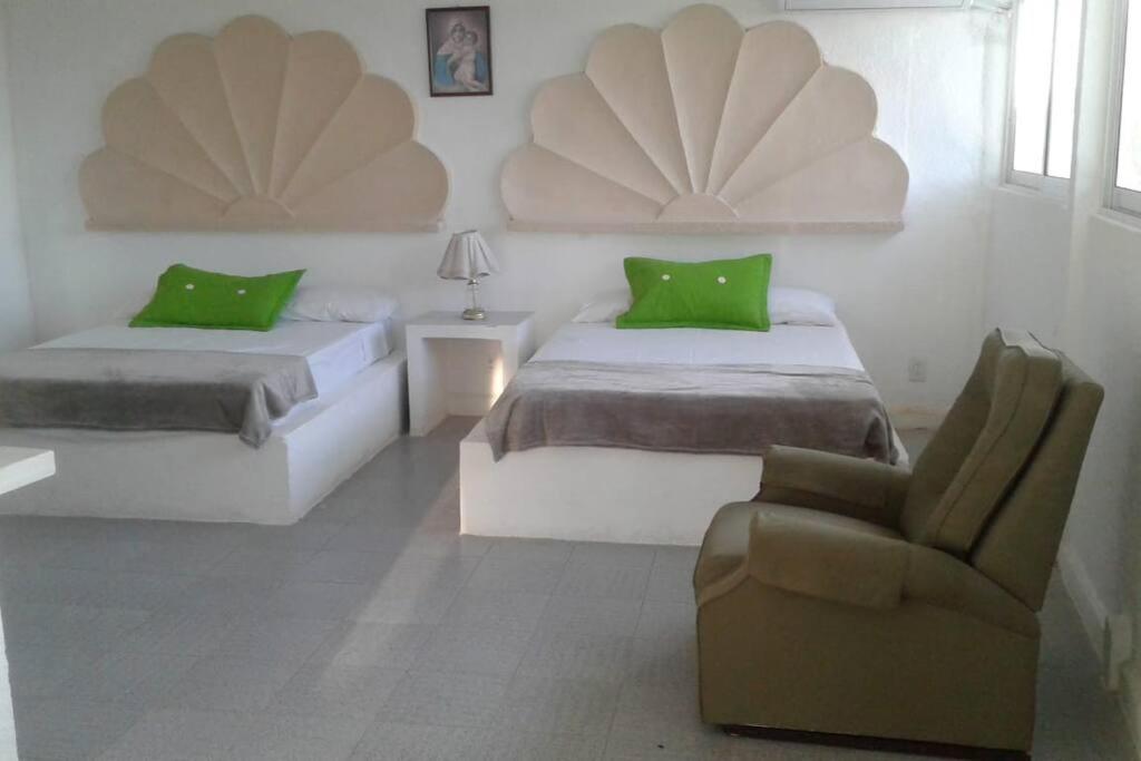 a hotel room with two beds and a chair at Casa con vista espectacular al mar con alberca in Acapulco