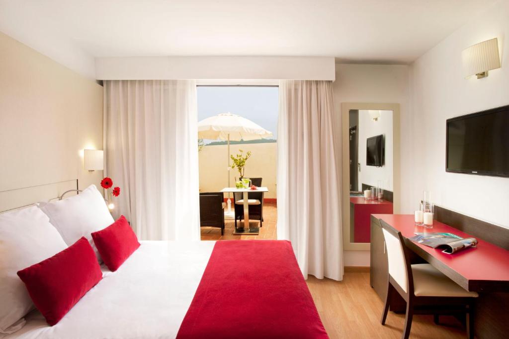 Habitació d´hotel amb llit, escriptori i para-sol a Grupotel Gravina, a Barcelona