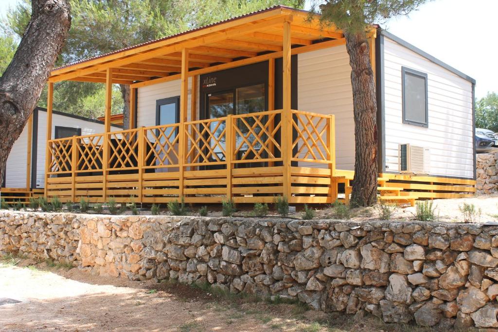 una casa con una gran terraza en una pared de piedra en Mobile Homes Jezera, en Jezera