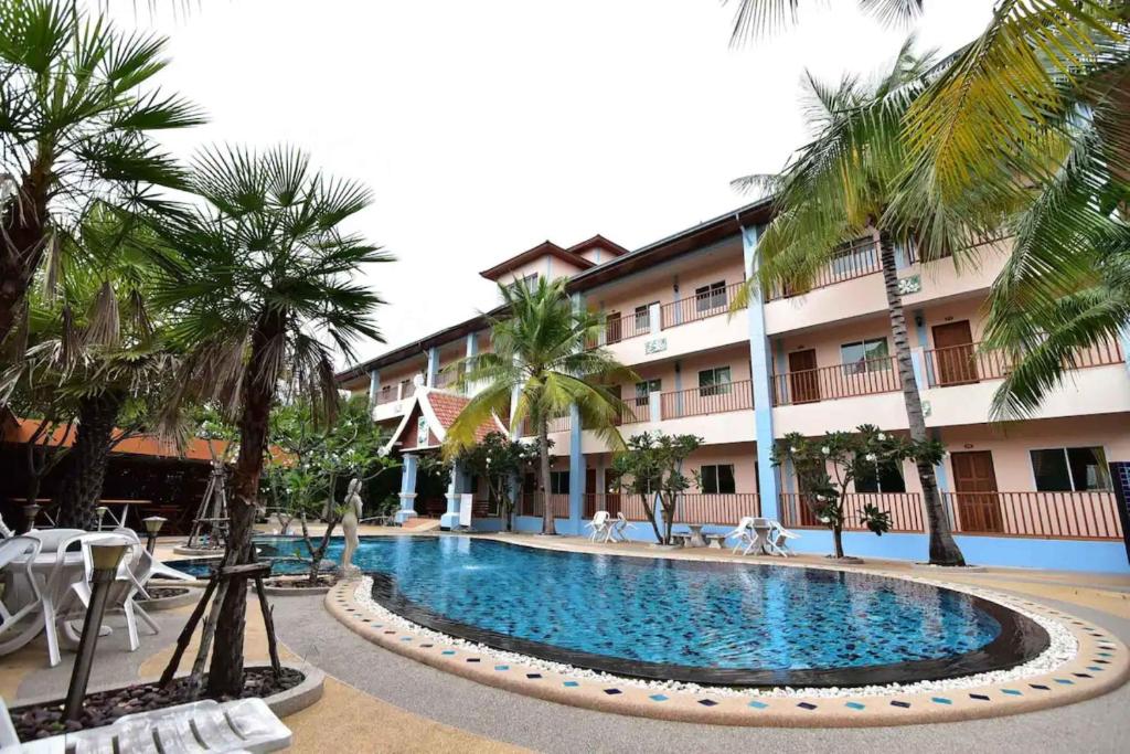 a swimming pool in front of a hotel with palm trees at Ampan Resort & Apartment in Nong Prue
