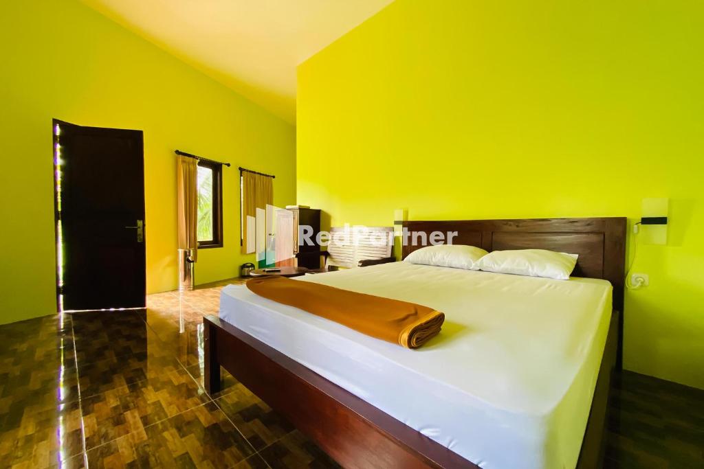 a bedroom with a large bed with yellow walls at Hotel dan Gazebo Pinggir Kali Prigen Mitra RedDoorz in Pasuruan