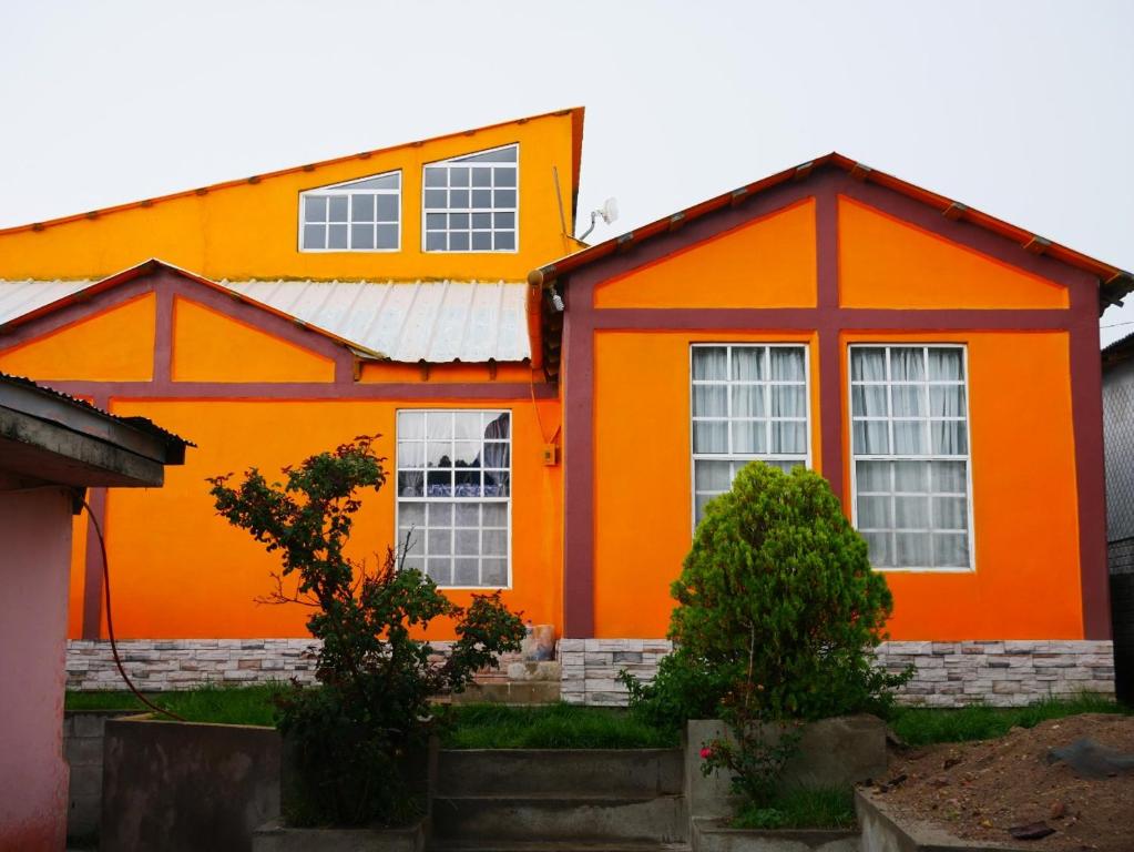 uma casa laranja com um telhado branco em Departamentos - Cabañas Sias em Creel
