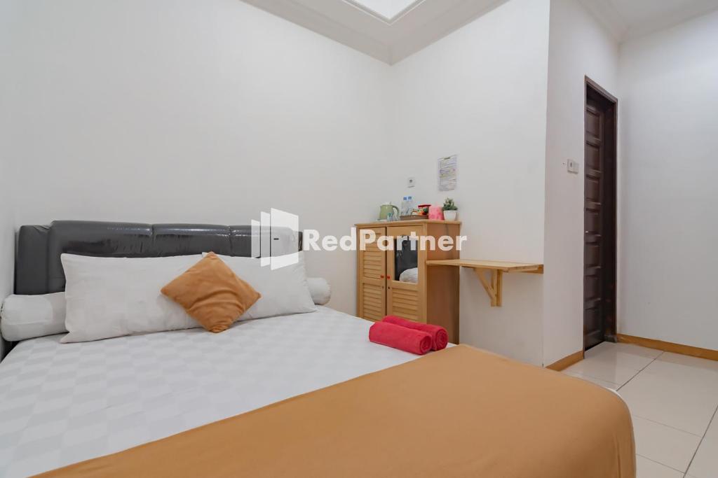 una camera da letto con un letto con cuscini bianchi e arancioni di Langkar Guest House Syariah Mitra RedDoorz a Samarinda