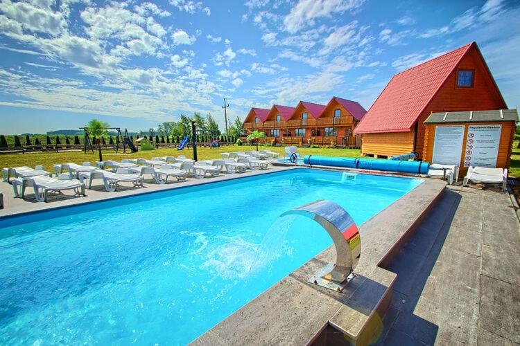 a large swimming pool with chairs and a red building at Holiday resort, Jaroslawiec in Jarosławiec