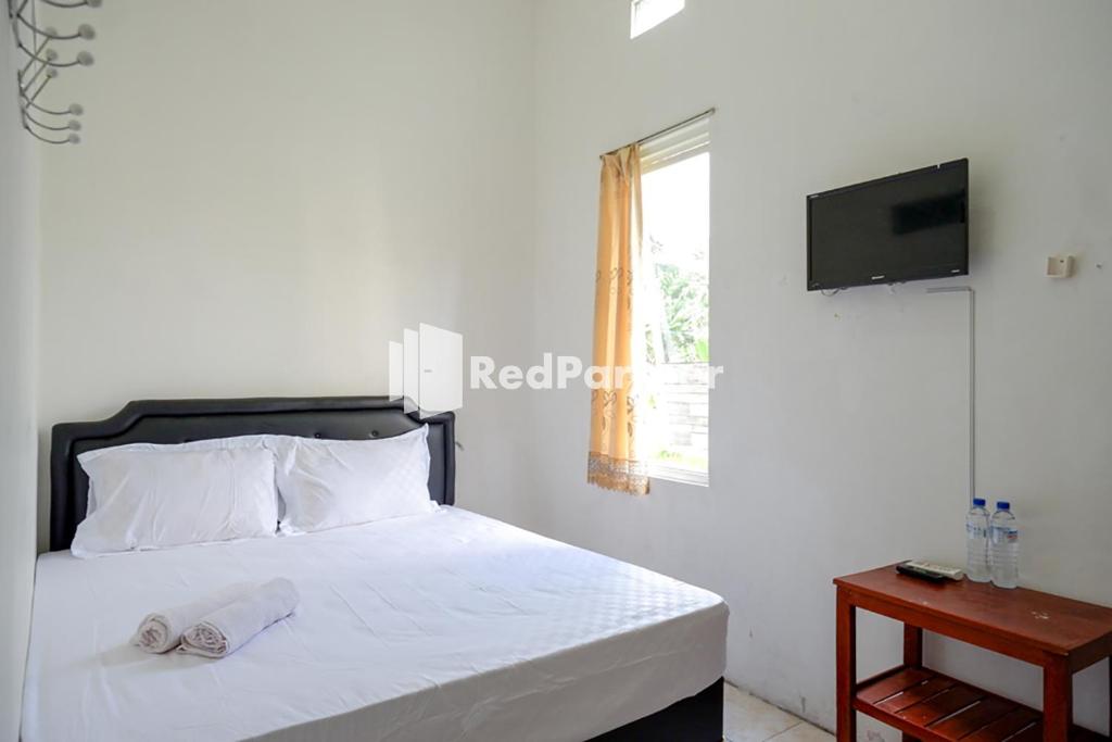 sypialnia z łóżkiem z białą pościelą i telewizorem w obiekcie Pringgondani Guest House At Pandanaran Hills Semarang w mieście Semarang