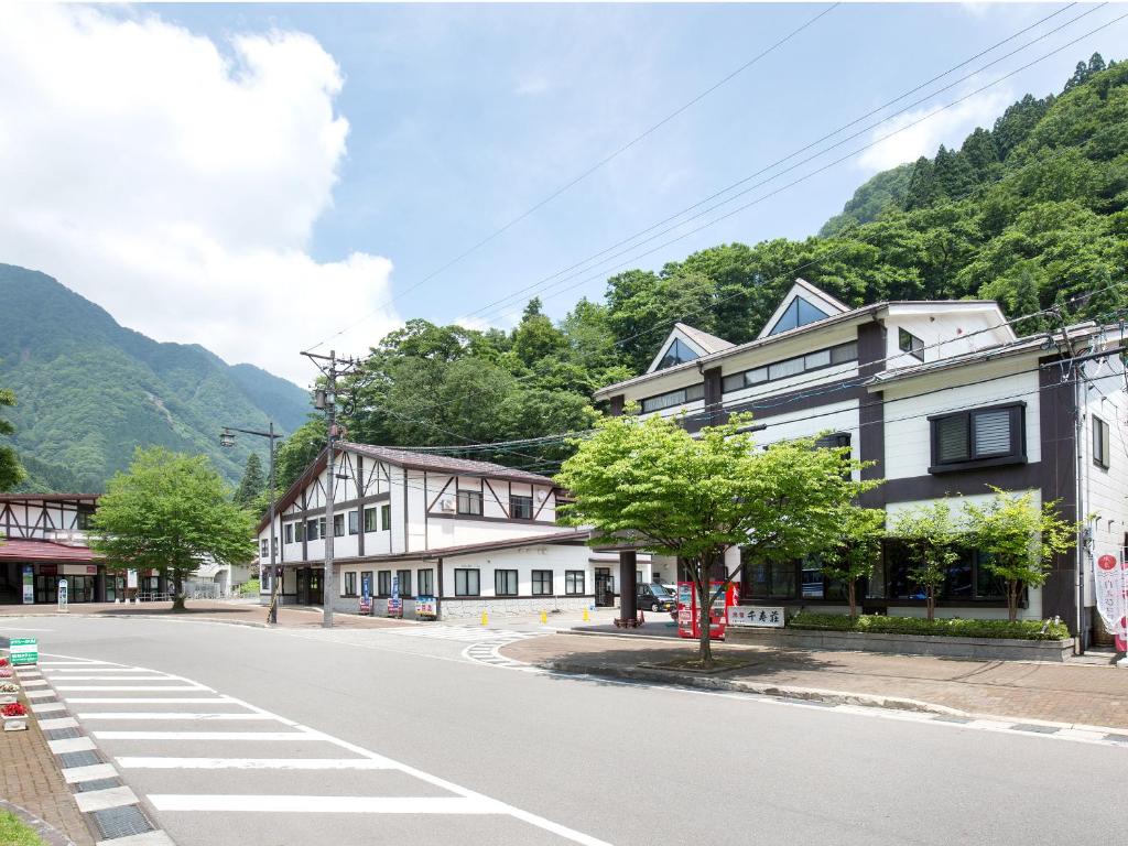una calle vacía en un pueblo con montañas en Tateyama Kurobe Alpine Route Senjuso 立山黒部アルペンルート千寿荘, en Tateyama