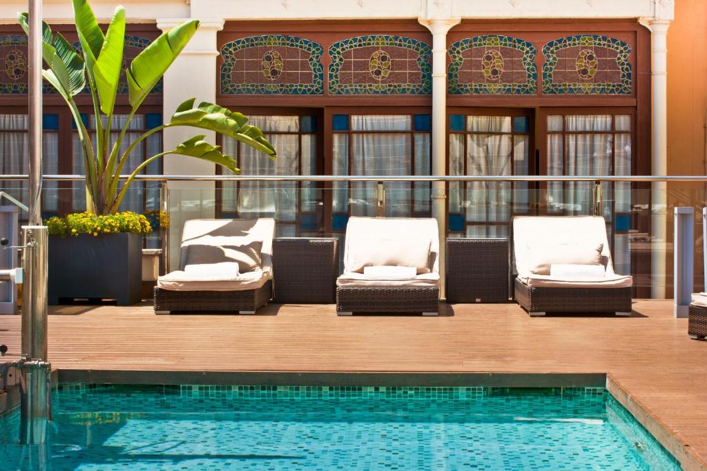 a pool with chaise lounge chairs next to a building at Grupotel Gran Via 678 in Barcelona