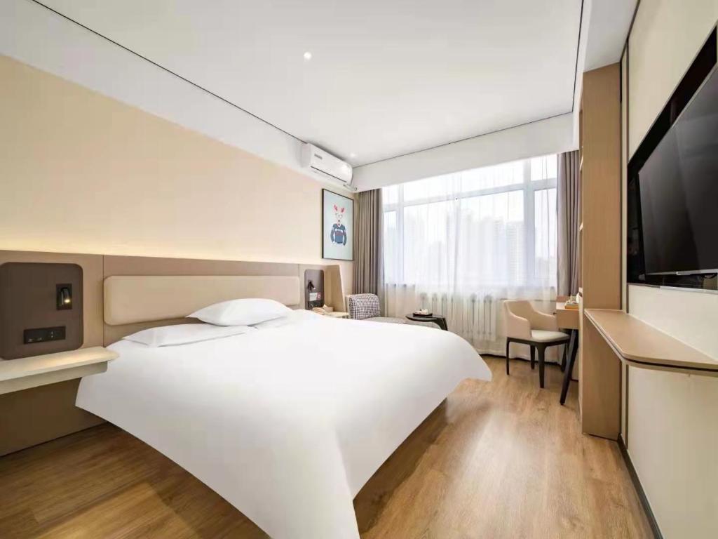 Cette chambre comprend un grand lit blanc et une télévision. dans l'établissement 银座佳驿酒店（郓城汽车站店）, à Yuncheng
