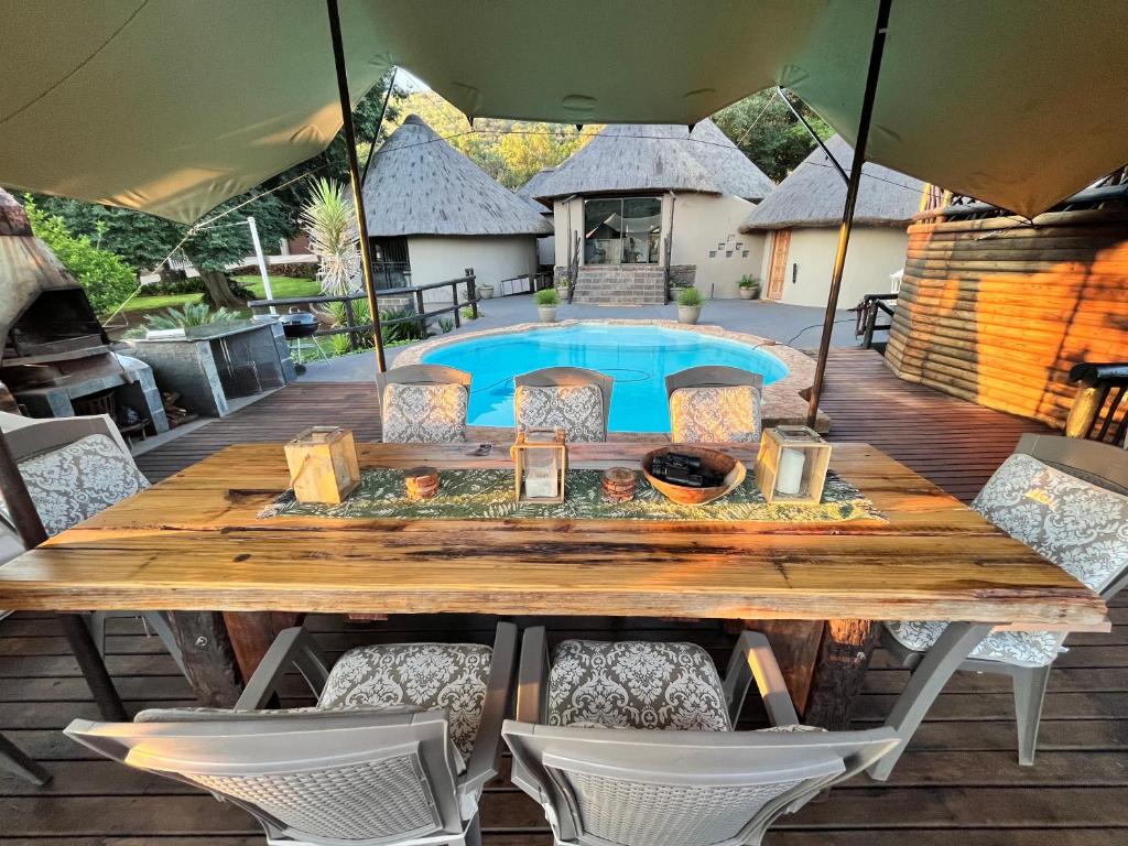 una mesa de madera y sillas en una terraza con piscina en Khululeka Guest Farm en Millvale