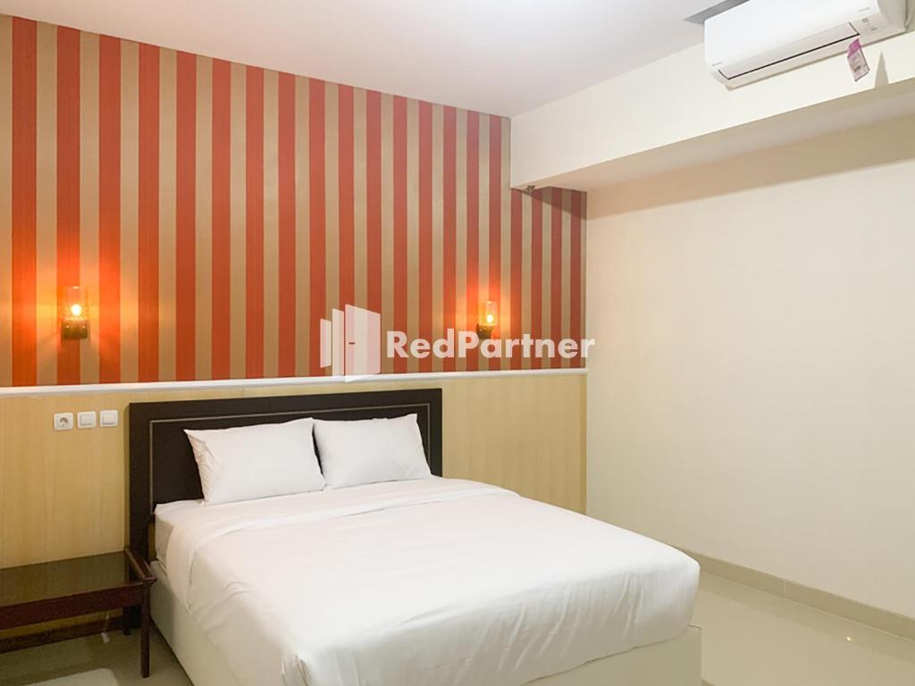 a bedroom with a white bed and a red striped wall at RedDoorz Syariah At Hotel Nuri Indah Dongkelan Yogyakarta in Bantul