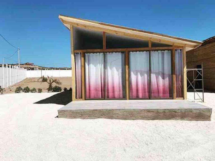 ein kleines Gebäude mit Vorhängen darauf in der Wüste in der Unterkunft Cabaña en Tongoy in Tongoy