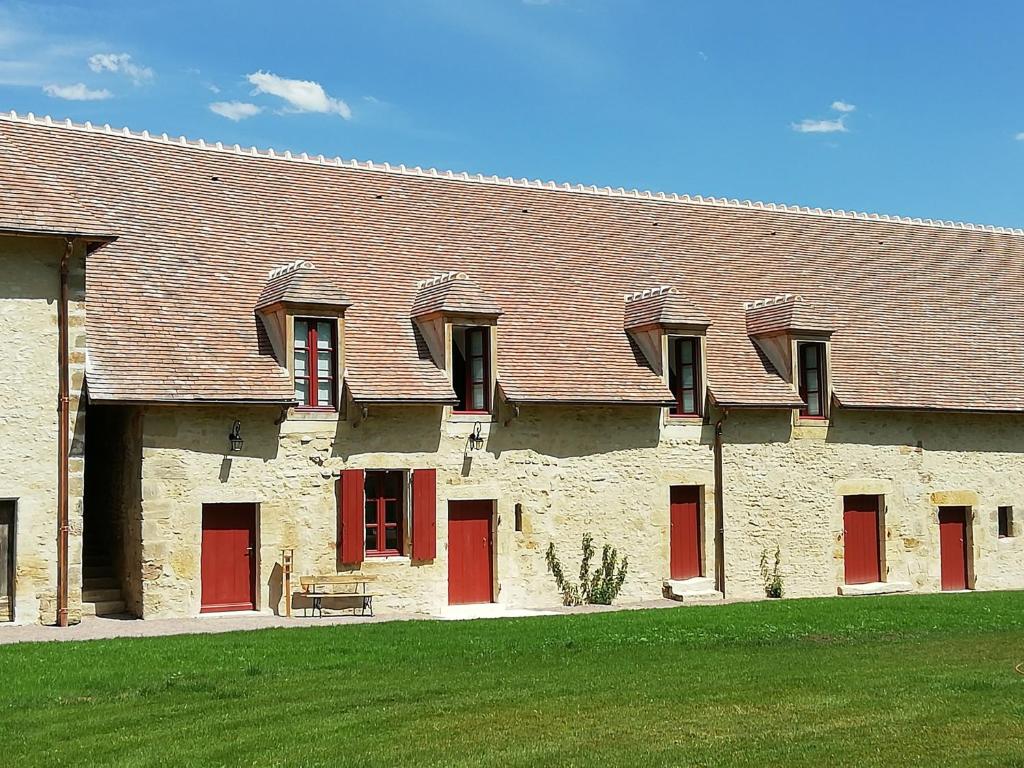 a large brick building with red doors and a grass field at Gîte Ainay-le-Vieil, 5 pièces, 8 personnes - FR-1-586-15 in Ainay-le-Vieil