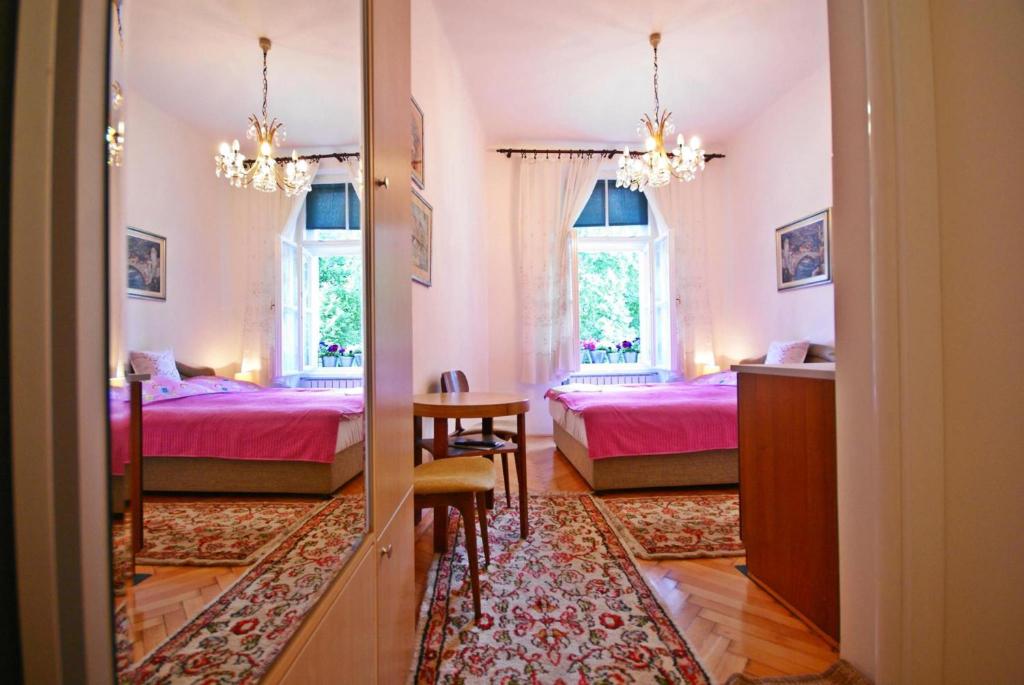 a bedroom with two beds and a table and a mirror at Studio Park in Sarajevo