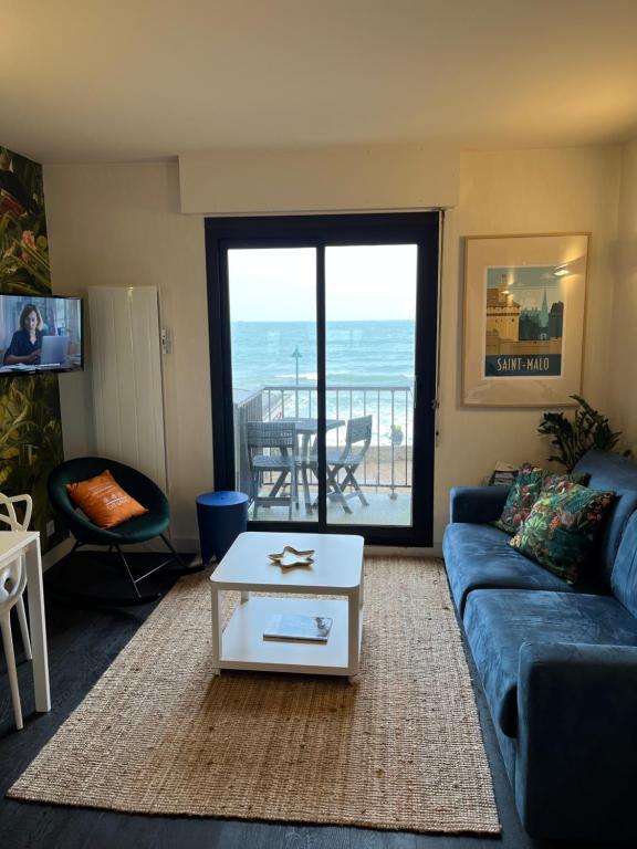- un salon avec un canapé bleu et une table dans l'établissement Emeraude, pleine vue de mer, à Saint-Malo