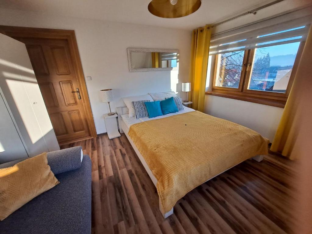 een slaapkamer met een bed met blauwe kussens en een raam bij Apartament Stanisława in Zakopane