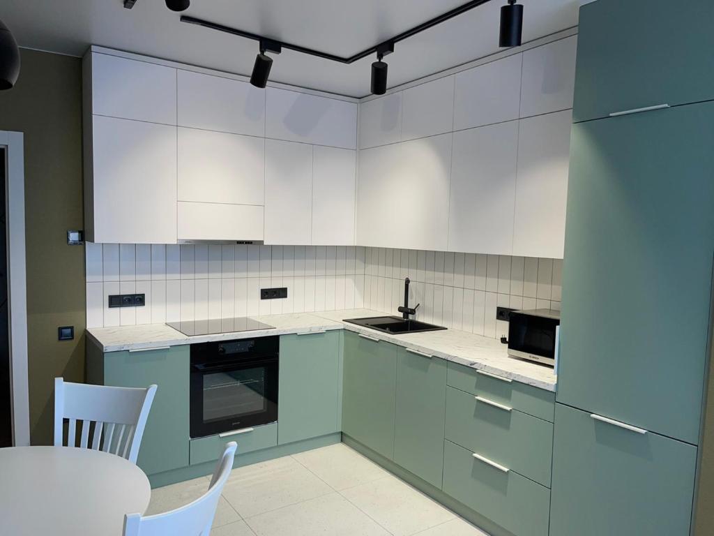 a kitchen with white cabinets and a table and chairs at PRESTIGE-CENTER in Rivne