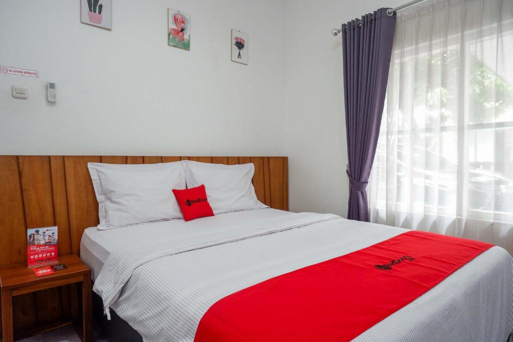 ein Schlafzimmer mit einem Bett mit einem roten Kissen darauf in der Unterkunft RedDoorz near XT Square 4 in Timuran