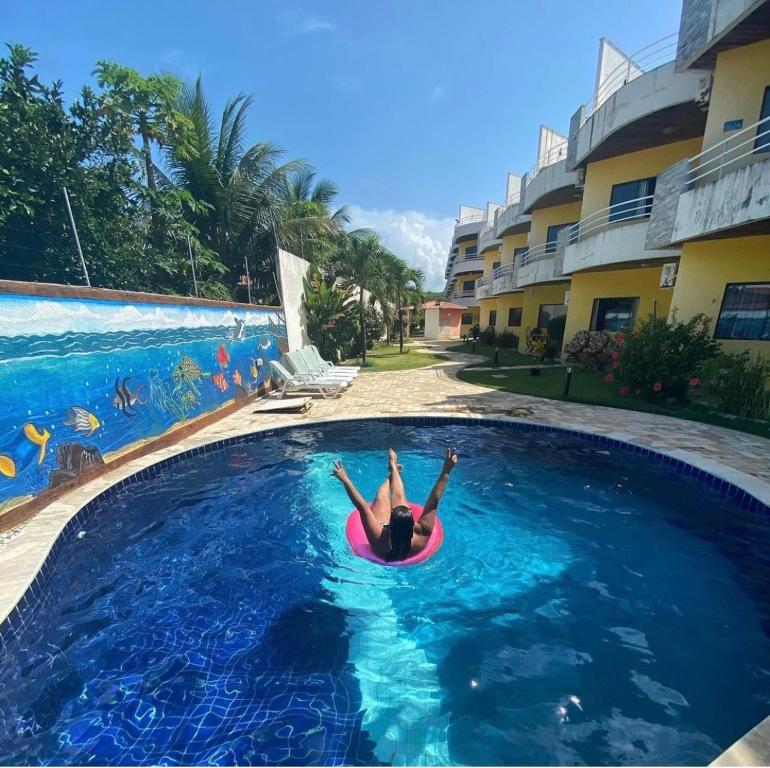 una persona sdraiata in una piscina di Ocean View Tabatinga a Nísia Floresta