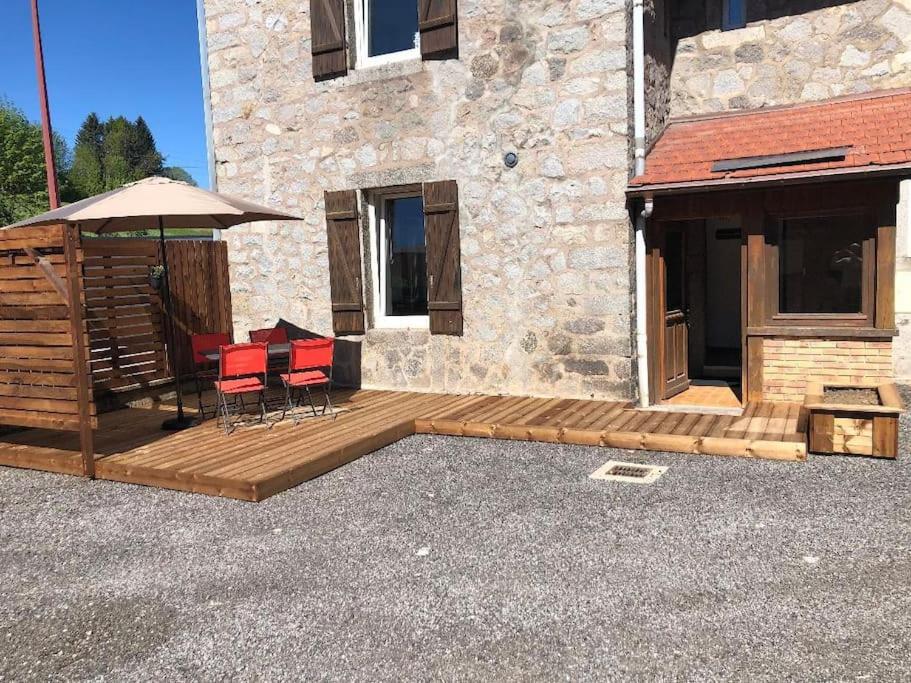 une terrasse en bois avec des chaises et un parasol à côté d'un bâtiment dans l'établissement Le Studio Polichinelle, à Gérardmer