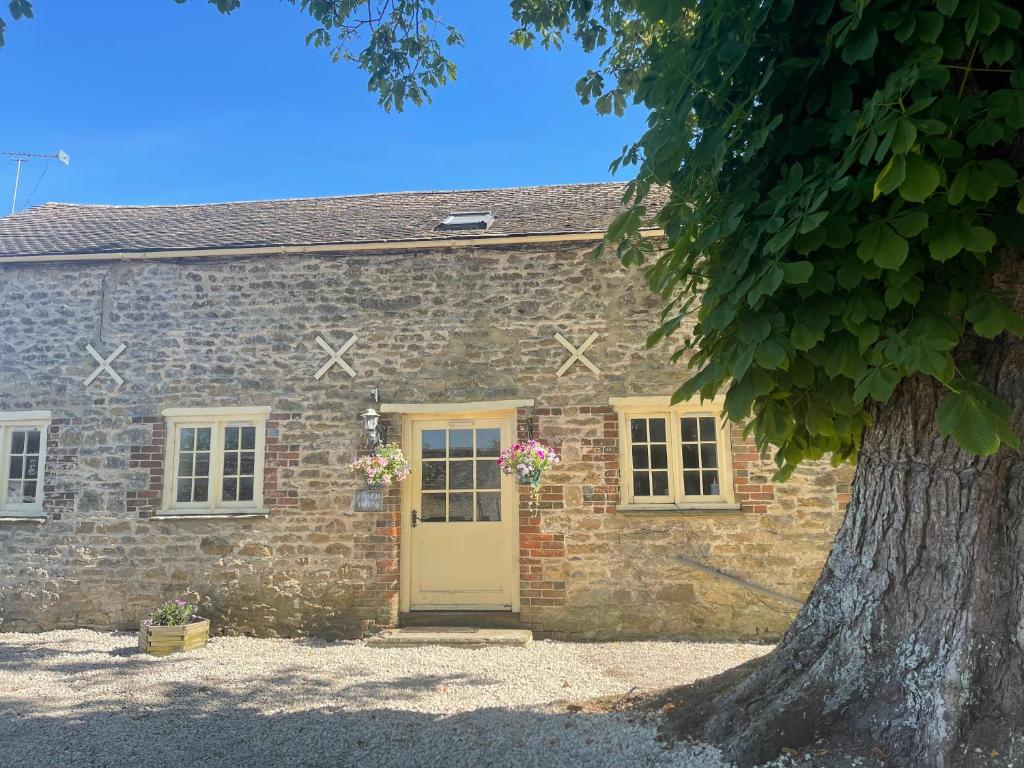 a stone house with a yellow door and a tree at Spacious Cotswold country cottage in Buscot