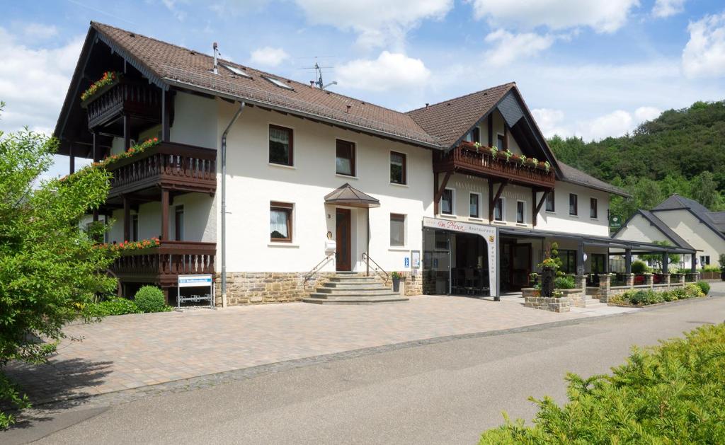 a large white building with a staircase in front of it at Restaurant - Pension Im Pfenn in Irrhausen