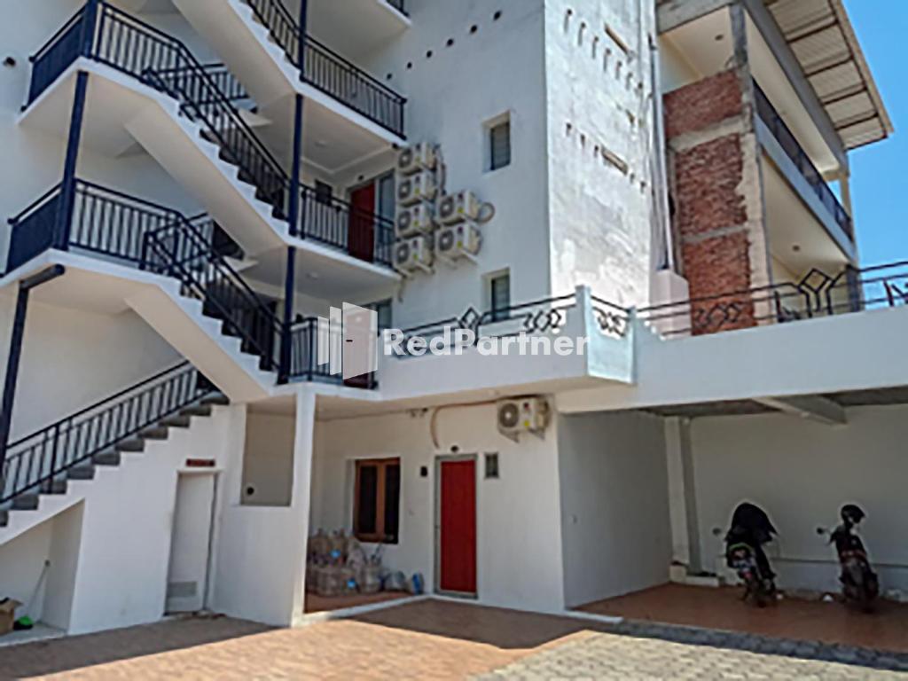 ein weißes Gebäude mit einer Treppe und einer roten Tür in der Unterkunft Hotel Trikatu Kendal near Taman Kota Weleri Mitra RedDoorz in Kendal