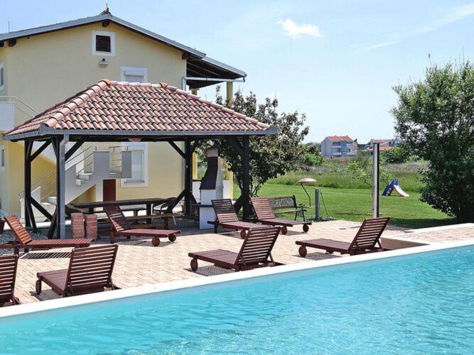 - un groupe de chaises et un kiosque à côté de la piscine dans l'établissement Apartments Lug 2, new and comfortable with pool, à Privlaka
