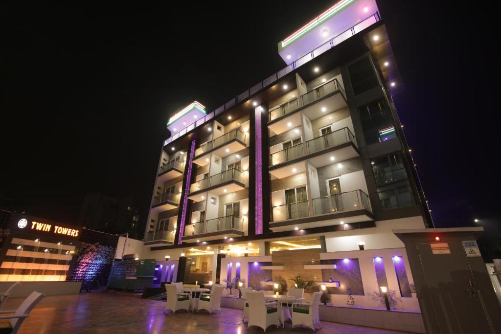 a hotel building with white tables and chairs at night at Twin Towers Inn in Greater Noida