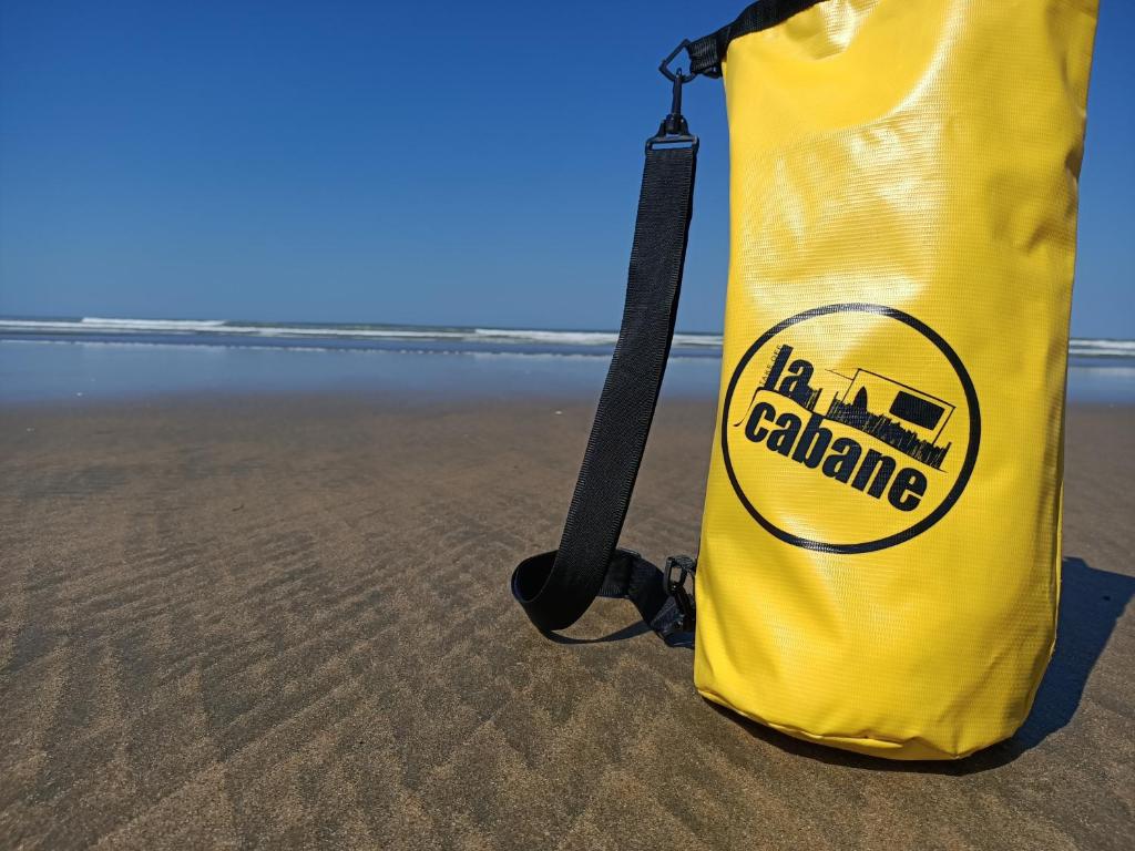 a yellow bag sitting on the beach at Pomme de Pin et Mimosa in Grand-Village-Plage