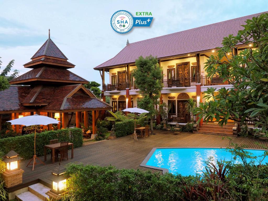 a resort with a swimming pool in front of a building at Amata Lanna Village อมตะล้านนาวิลเลจ in Chiang Mai