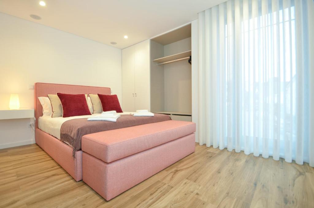 ein Schlafzimmer mit einem rosa Bett und einem großen Fenster in der Unterkunft Oliva Teles 53 Apartments in Arcozelo