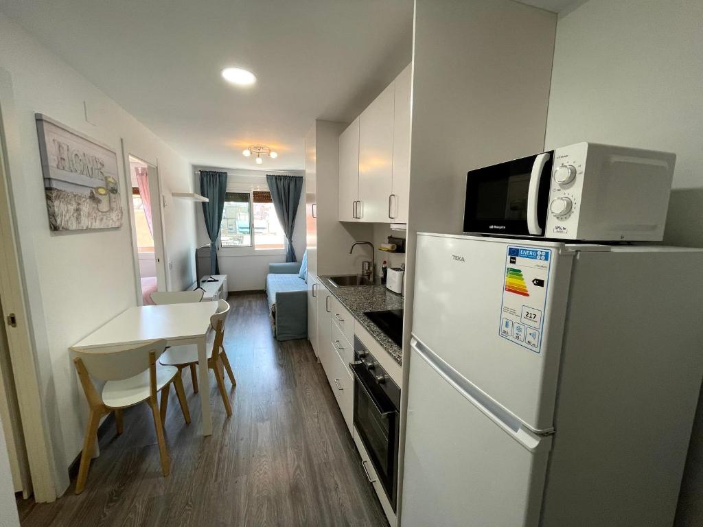 a kitchen with a refrigerator and a table with chairs at Sant Adria Beach apartment Wi-Fi Parking Free in Sant Adria de Besos