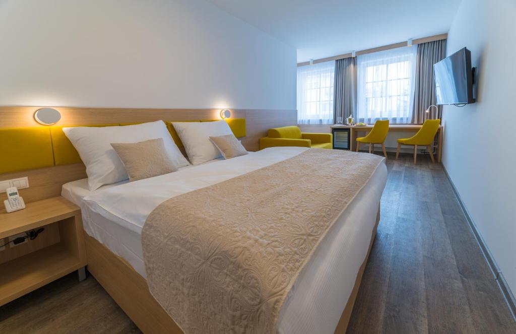 ein Hotelzimmer mit einem großen Bett und Stühlen in der Unterkunft Wellness Hotel IRIS in Pavlov