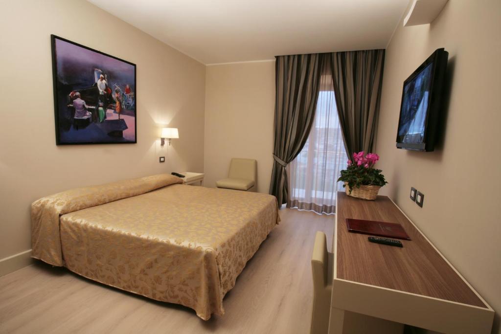 a hotel room with a bed and a desk and a television at Hotel Mirasole International in Gaeta