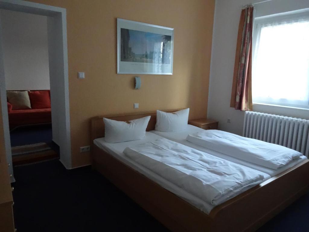 a bedroom with a bed with white sheets and a window at Hotel Süden in Berlin