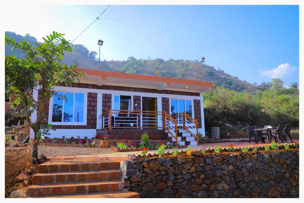 a house with a stone wall in front of it at Sai Siddhigiri Villa in Mahabaleshwar