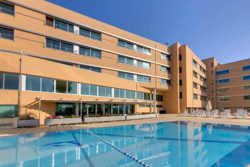 um hotel com piscina em frente a um edifício em TRYP by Wyndham Porto Expo Hotel em Leça da Palmeira