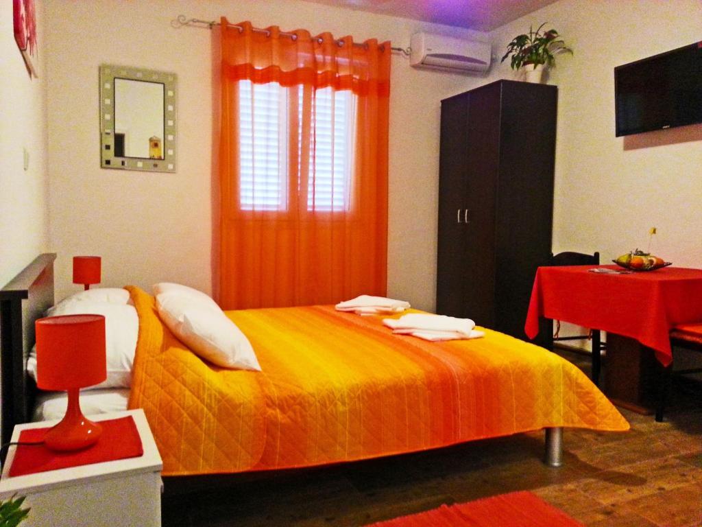 ein Schlafzimmer mit einem Bett mit einer orangefarbenen Decke in der Unterkunft Apartments and Rooms King in Mokošica