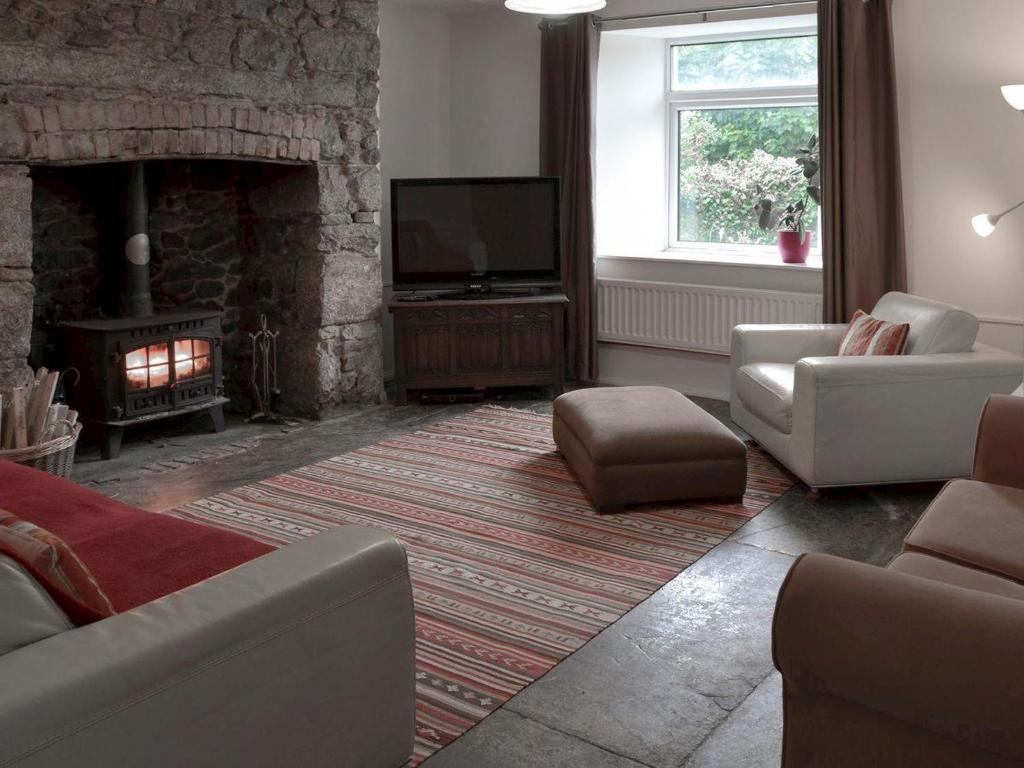 a living room with a fireplace and a television at The Old Farmhouse at Mena in Bodmin