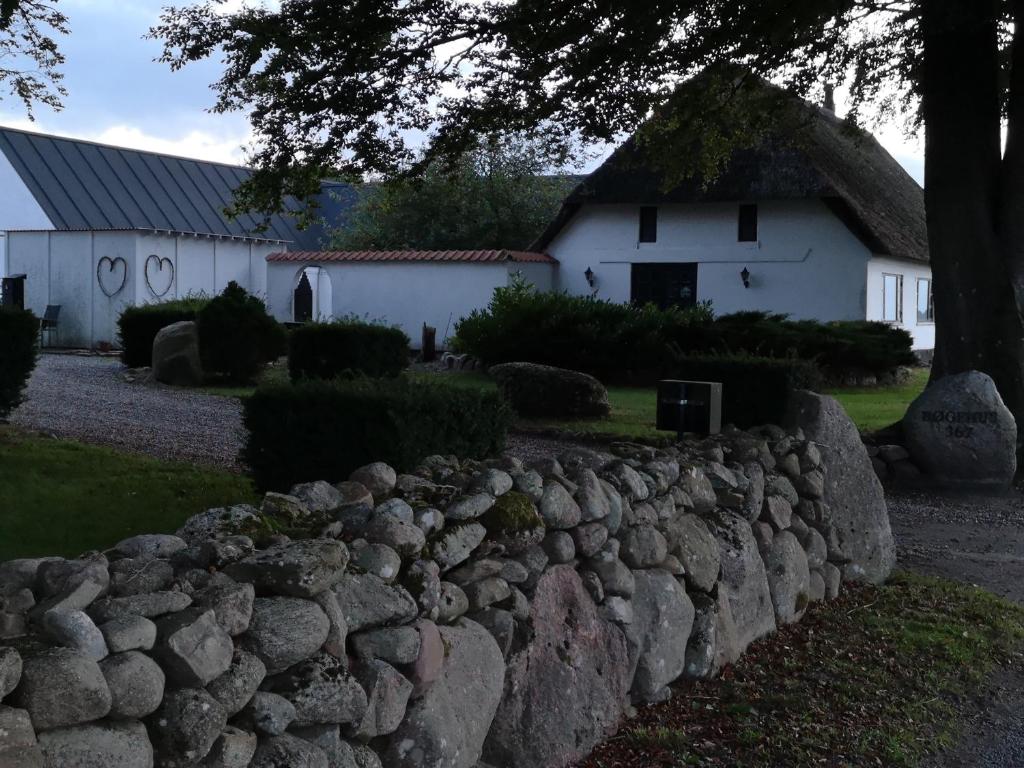 a stone retaining wall in front of a white house at Bøgehus in Vejle