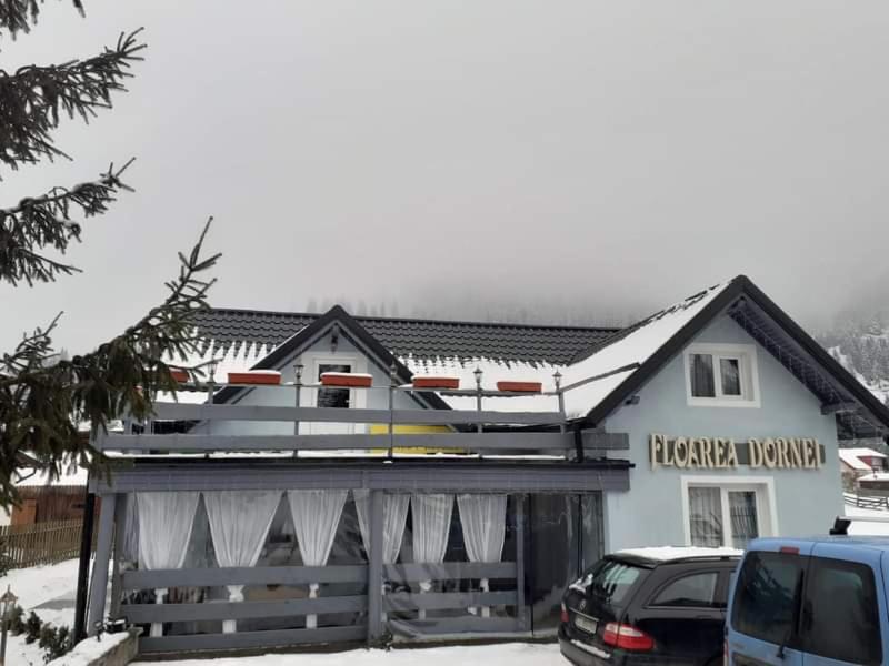 a building with snow on the top of it at Pensiunea Floarea Dornei in Şarul Dornei