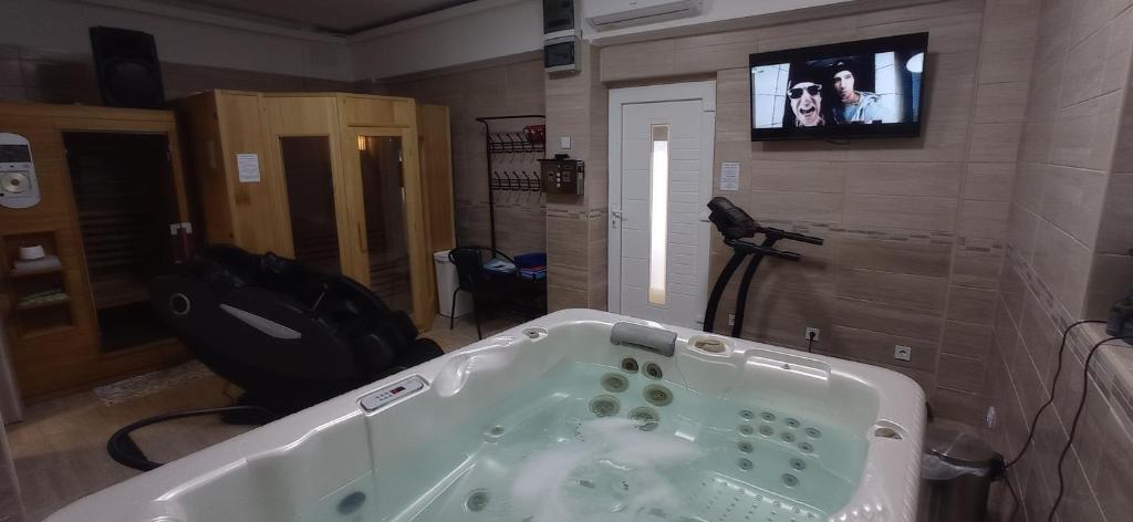 een badkamer met een bad en een tv aan de muur bij Robitel Wellness Vendégház Veszprém-Gyulafirátót in Veszprém