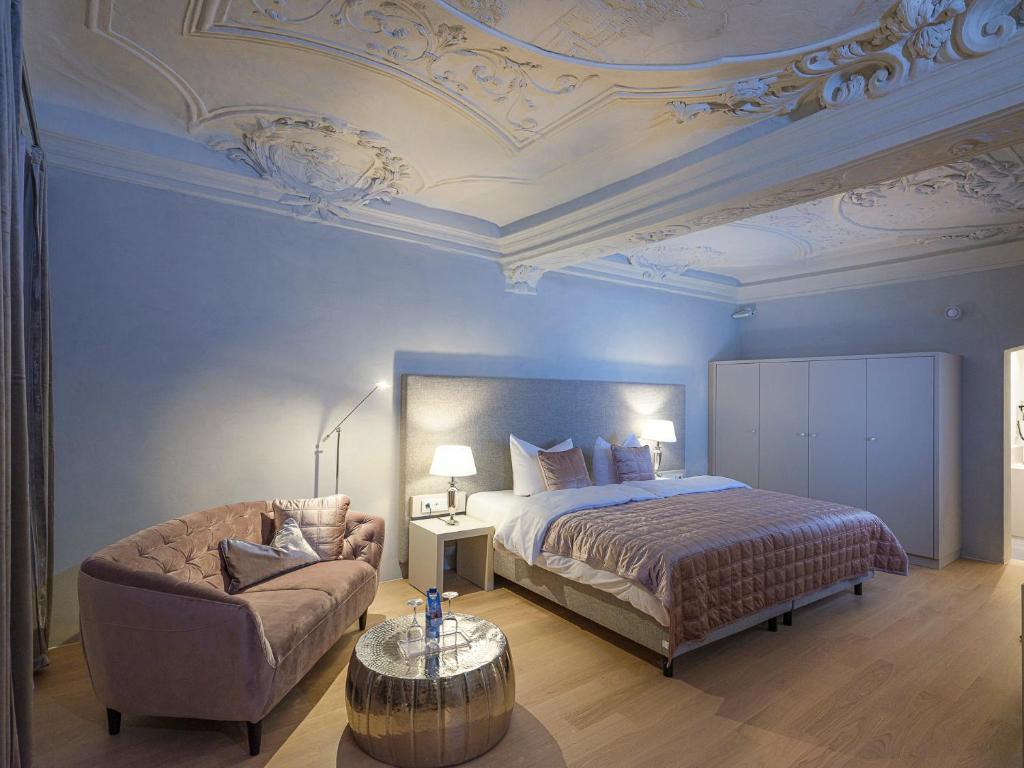 - une chambre avec un lit, une chaise et un canapé dans l'établissement Hotel Post, à Burghausen