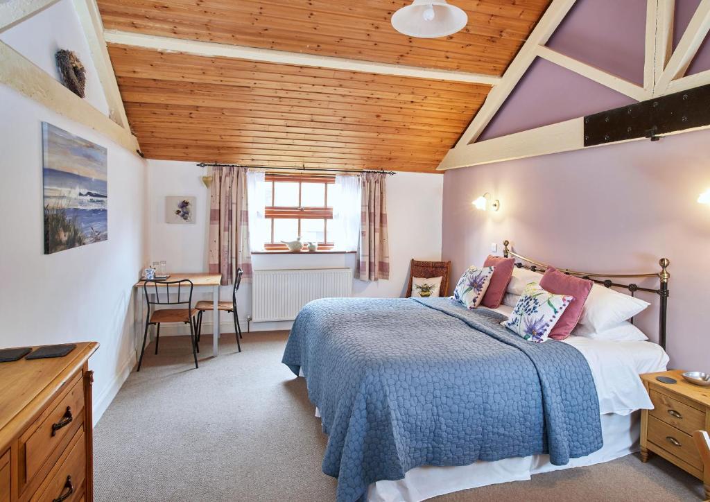 a bedroom with a bed and a wooden ceiling at Dairy Barns in Hickling